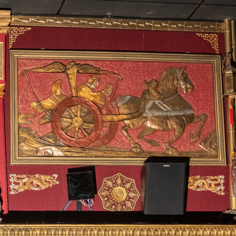 Chinese Gilt Chariot Relief Wall Art-Right: This striking piece of Chinoiserie features a high-relief carved panel depicting a traditional horse-drawn chariot with regal figures, finished in an opulent gold-tone gilt over a vibrant red textured