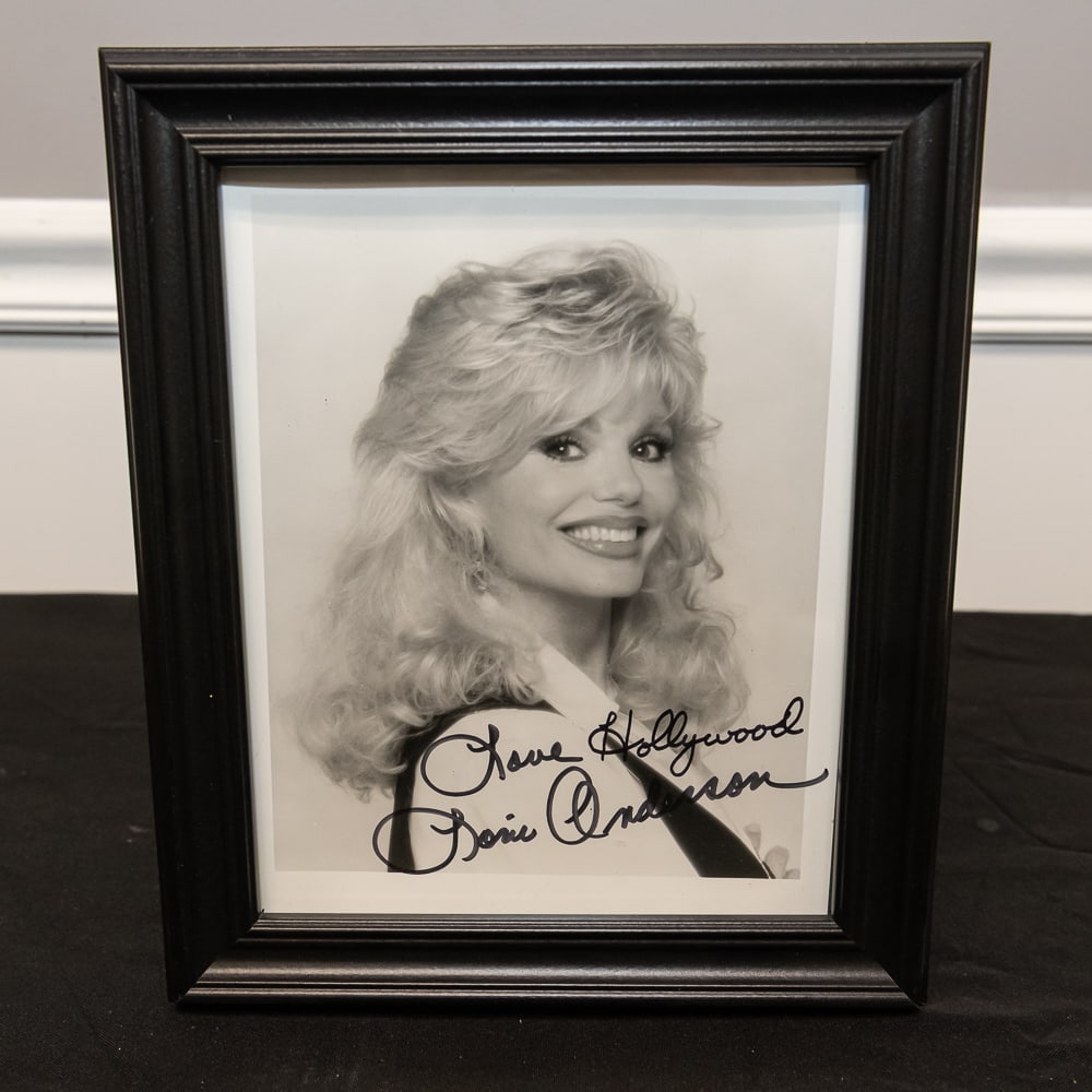 Framed Signed Loni Anderson Hollywood Photo 8x10: This vintage black-and-white promotional photograph captures the classic 1980s aesthetic, featuring a stylized portrait of the iconic WKRP in Cincinnati star, Loni Anderson. The piece is hand-signed i