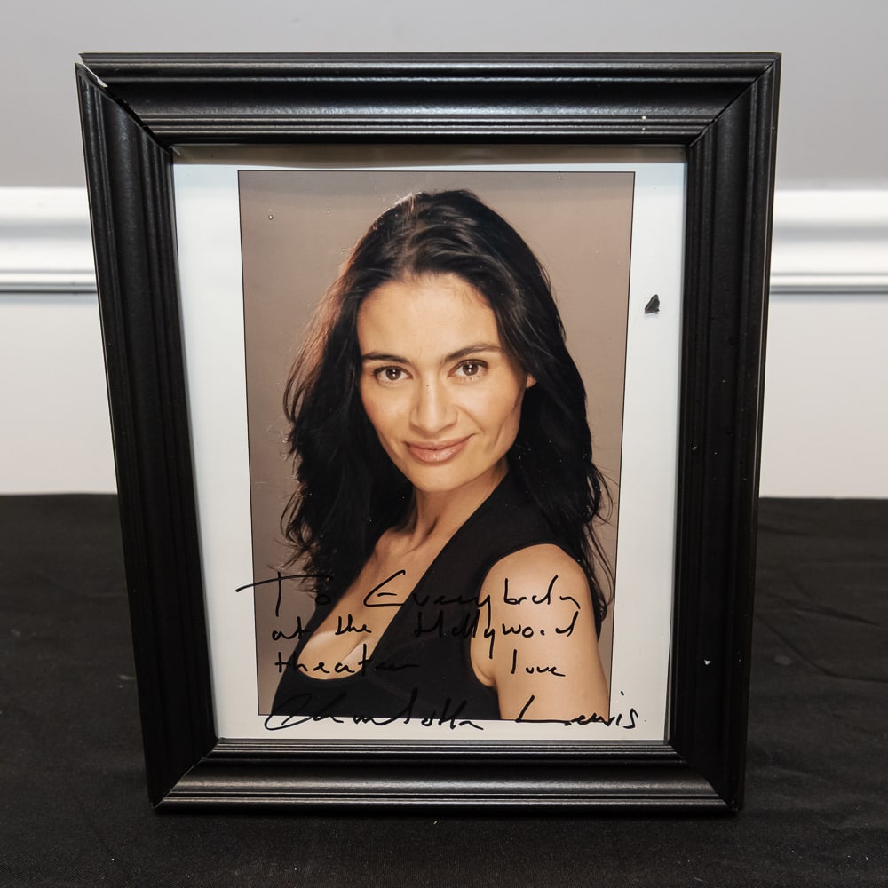 Framed Charlotte Lewis Signed Photo 8x10: This is a captivating 8"x10" color publicity photograph of actress Charlotte Lewis, best known for her roles in The Golden Child and Pirates. The piece features a bold, hand-signed inscription in blac