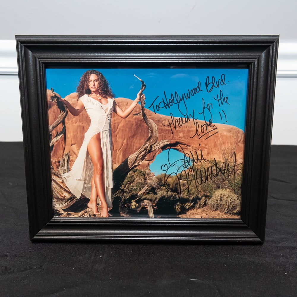 Framed Signed Dani Manthel Photo 8x10: This striking piece features an original autographed 8x10 color photograph of model and actress Dani Manthel, posed elegantly against a desert rock formation. The piece is inscribed "To Hollywood Blvd
