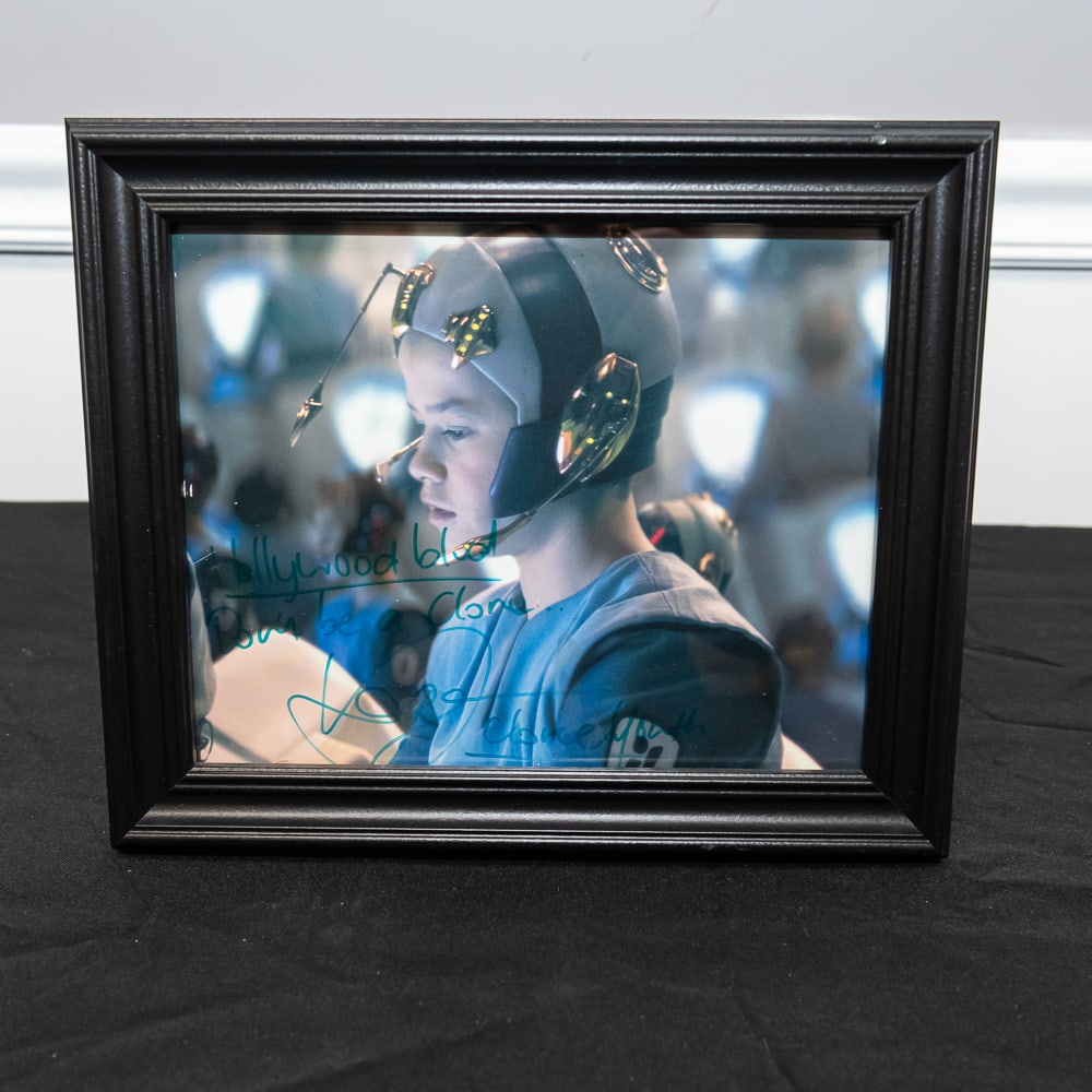 Framed Signed Star Wars Clone Youth Photo 8x10: This is a captivating 8"x10" color photograph featuring a "Clone Youth" from the Star Wars prequel era, specifically depicting the training sequence on Kamino from Episode II: Attack of the Clones. Th