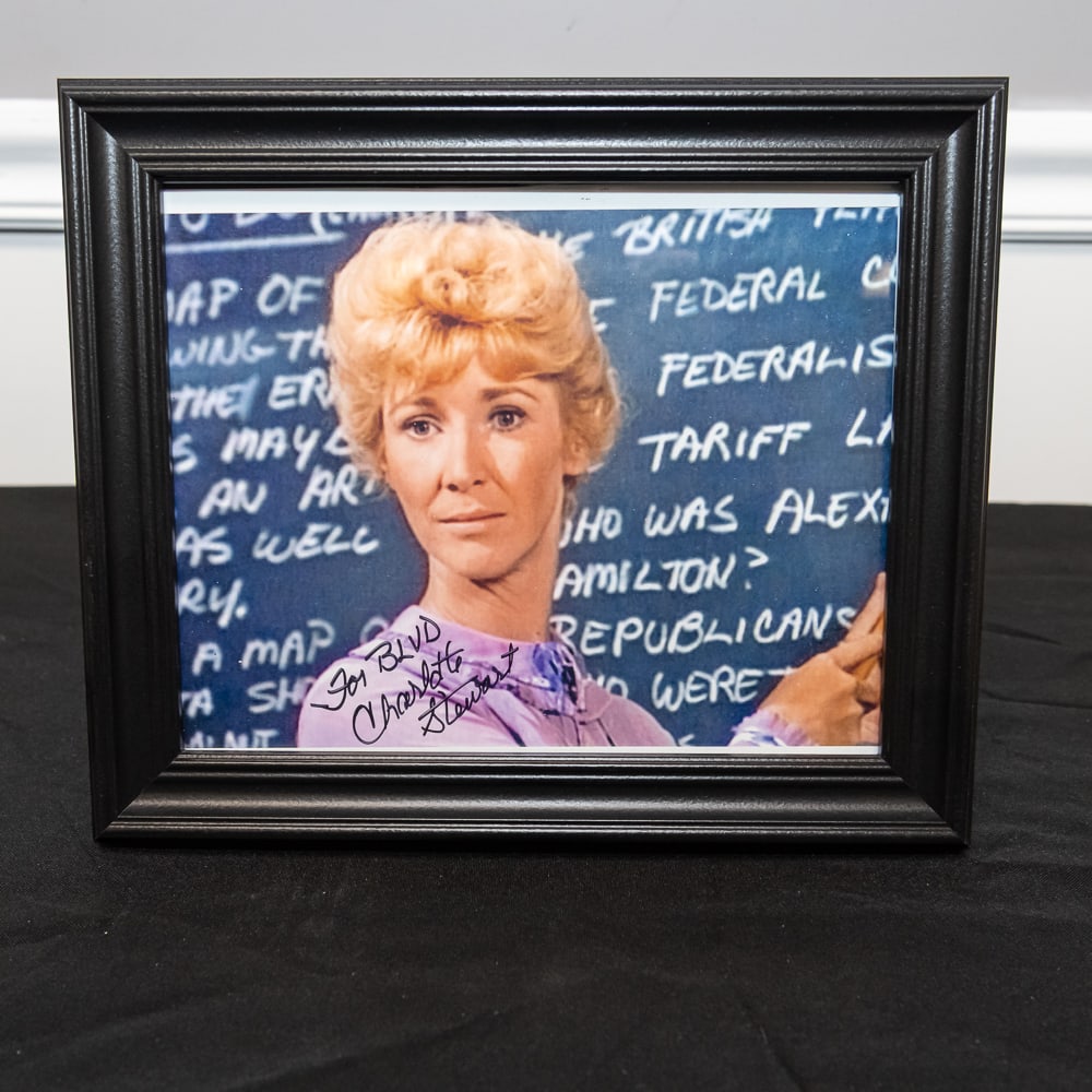 Framed Charlotte Stewart Autographed Photo 8x10: This is a wonderful piece of television history featuring Charlotte Stewart in her iconic role as Miss Beadle from the beloved series Little House on the Prairie. The 8x10 color photograph captures he