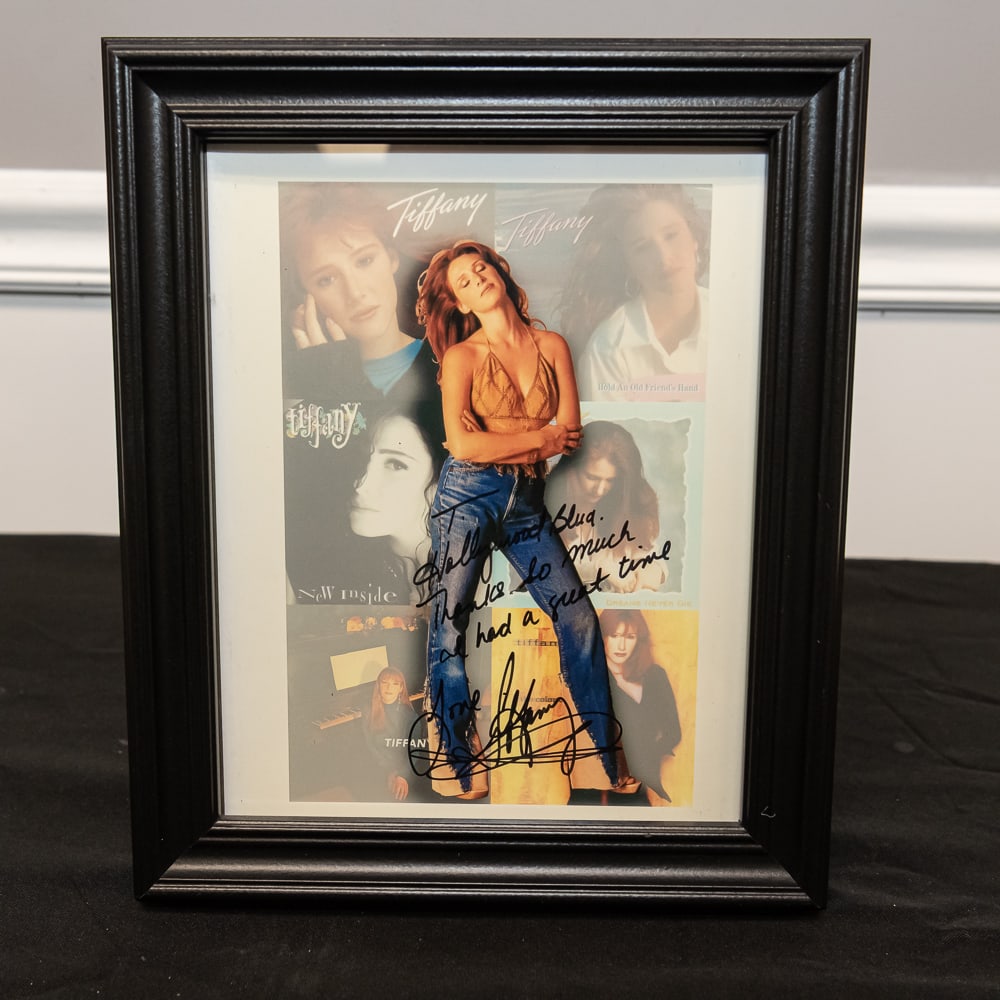 Framed Tiffany Autographed Collage Photo 8x10: This 8" x 10" framed presentation features 80s pop icon Tiffany, showcasing a dynamic central cutout of the singer layered over a collage of her most iconic album and single covers, including Hold An