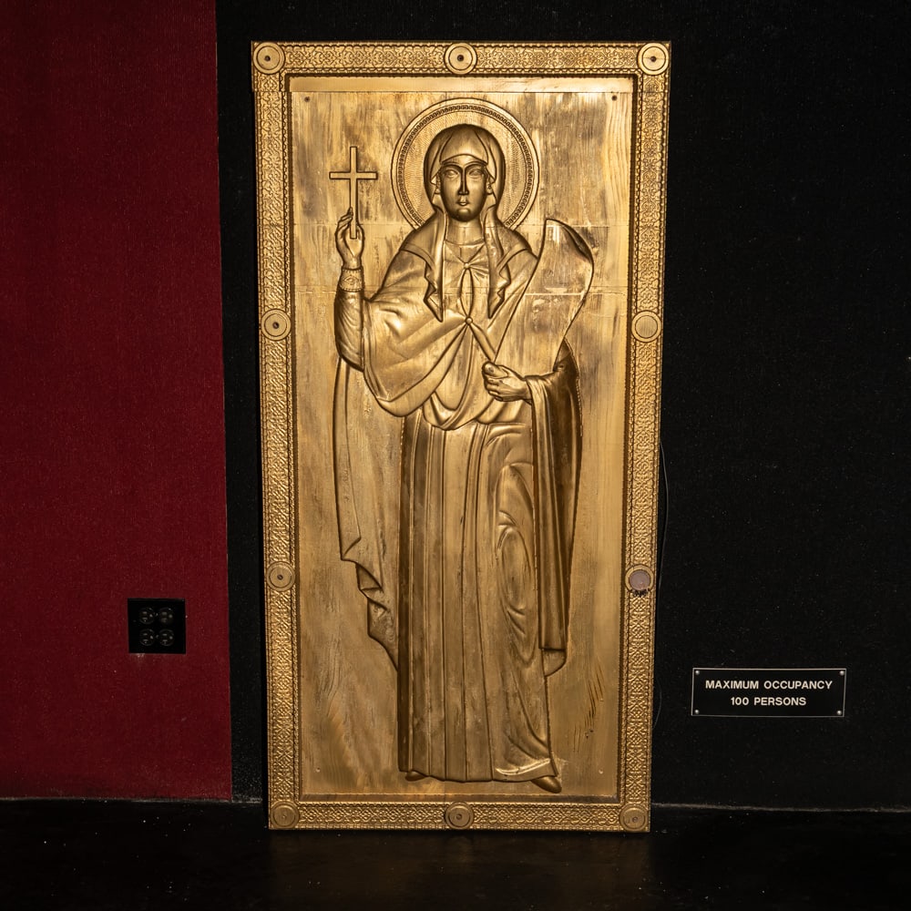 Large Carved Style Wooden Orthodox Saint Icon: This striking relief-carved wooden panel style depicts a female Orthodox saint, possibly St. Paraskevi or St. Helena, holding a cross and a scroll. Executed in a traditional Byzantine style with an in