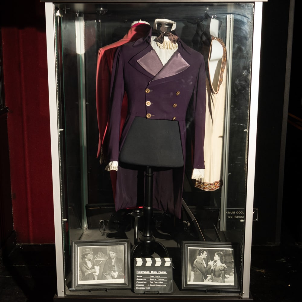 Tony Curtis Costume From The Purple Mask: Tony Curtis screen worn costume from the 1955 movie, The Purple Mask. In good condition. Comes with display torso, 2 framed B&W stills from the movie, and a clapboard. Does not include glass case.