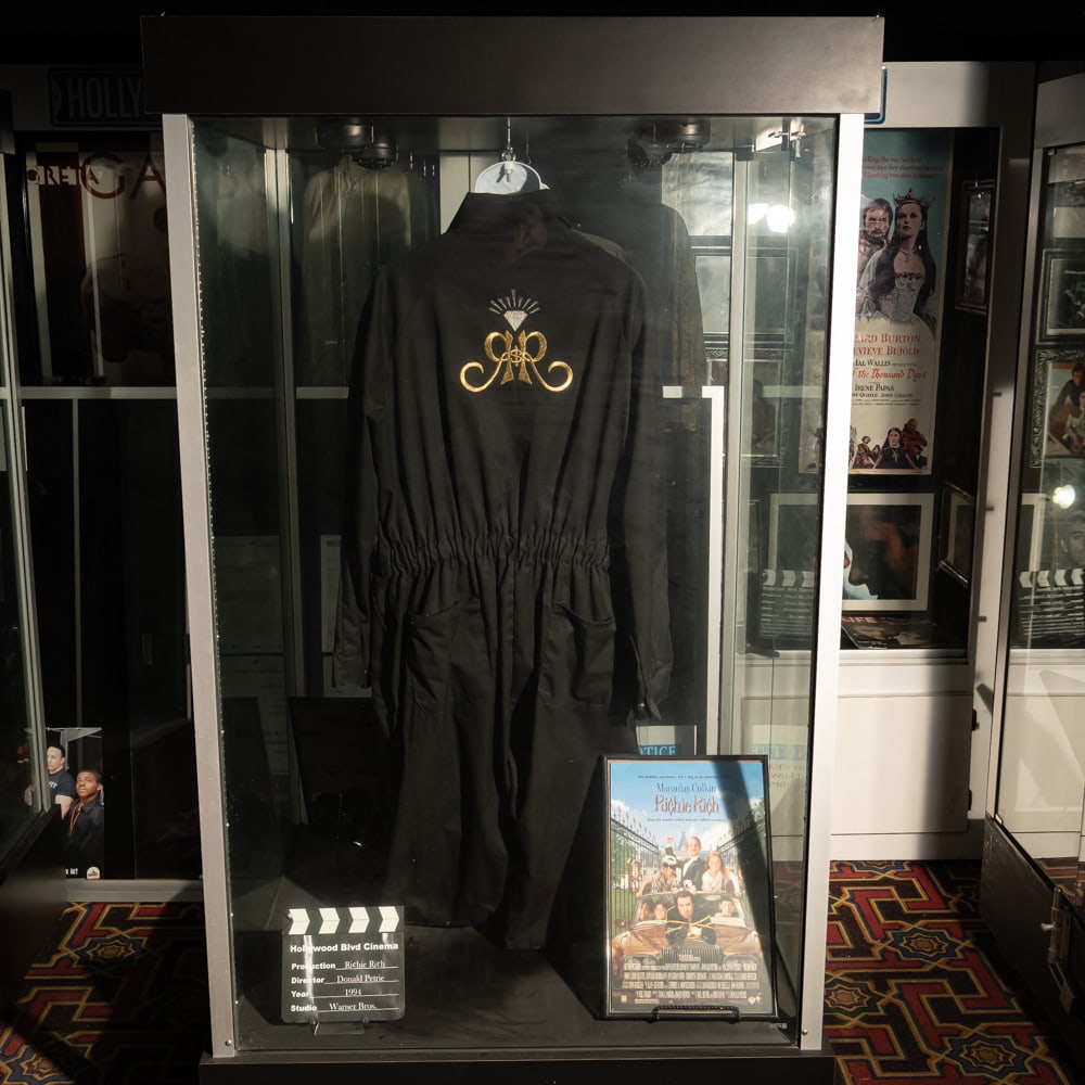 Richie Rich Display: Black jumpsuit with gold embroidered logo on the back from the 1991 Warner Bros. movie, Ritchie Rich. In good condition. Comes with a display torso and a framed movie promotional poster. Does not incl