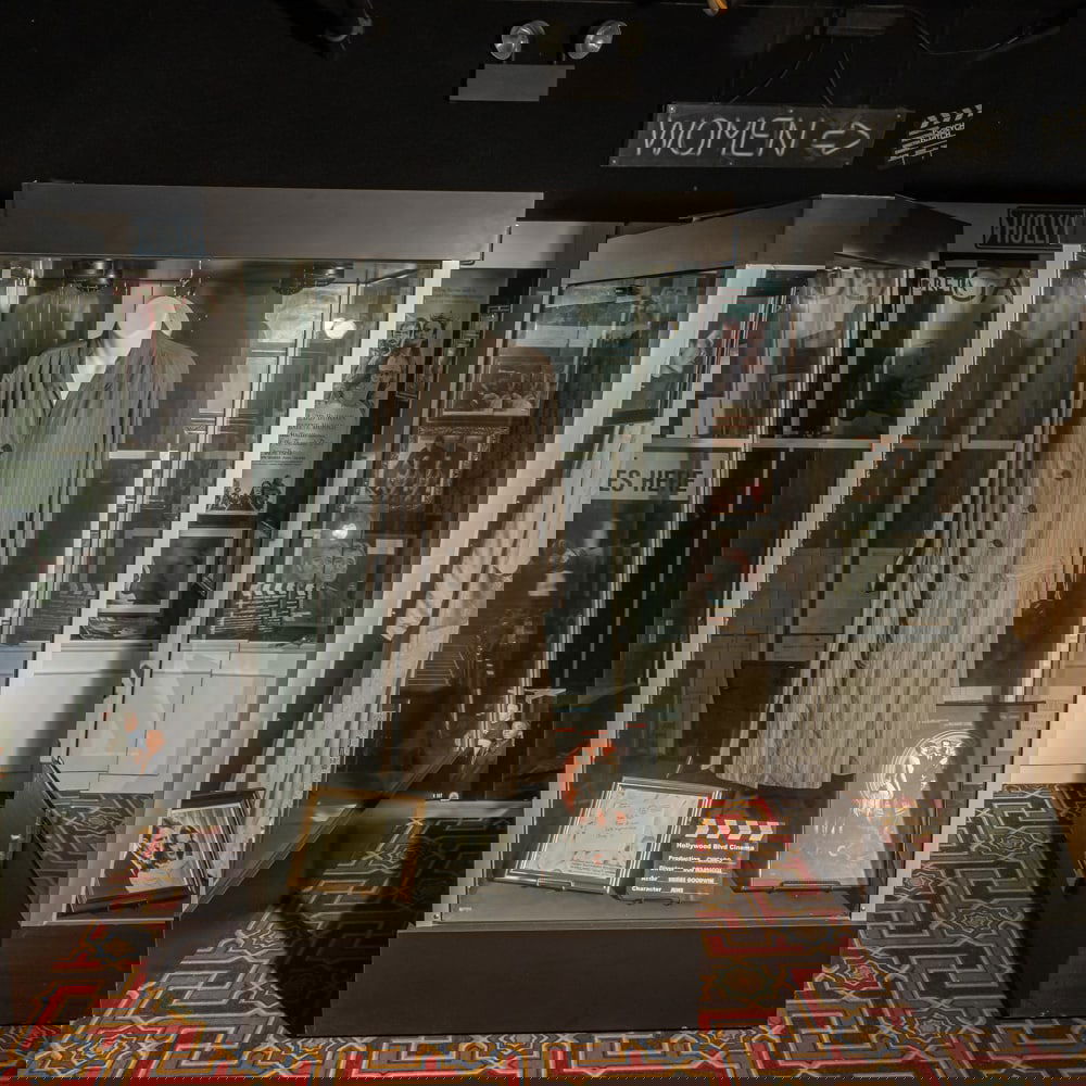 Professional 4-Sided Glass Display Case: This is a substantial, retail-grade mobile display showcase featuring a robust black laminate base and cap with clear glass panels on all four sides, offering 360-degree visibility for high-value