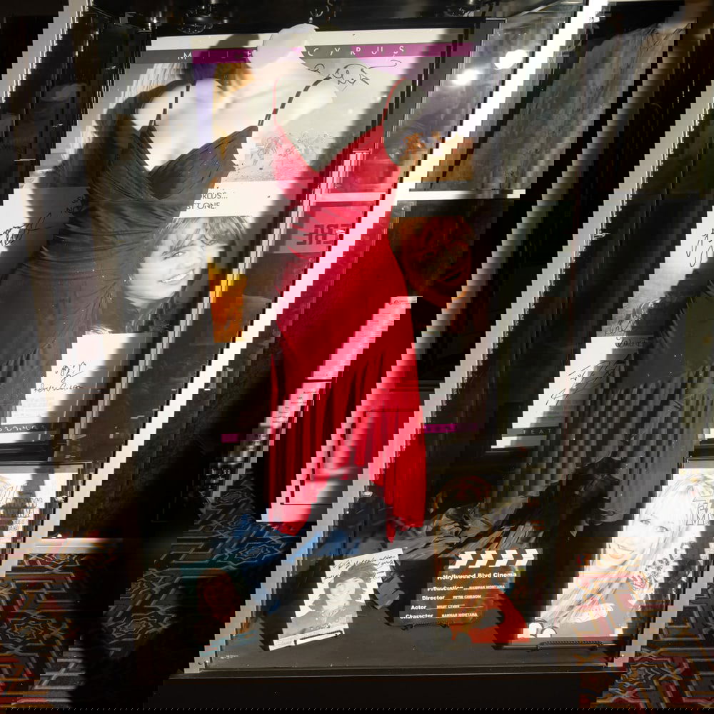 Hannah Montana Miley Cyrus Dress: Lot includes a Miley Cyrus screen worn dress from the 2009 movie Hannah Montana, display torso, a cast signed one sheet movie poster from the movie, an signed picture of actor Mitchel Russo, and a