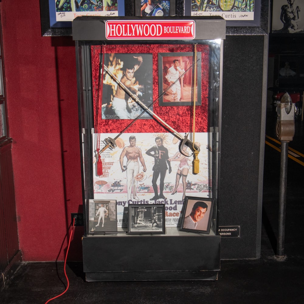 Wood & Glass Display Case (Tony Curtis): Display case with glass top and front with wood sides and wood sliding access doors in back In good condition. Measures 48" wide, 38" tall, 20" deep. Contents of case not included, sold as previous lo