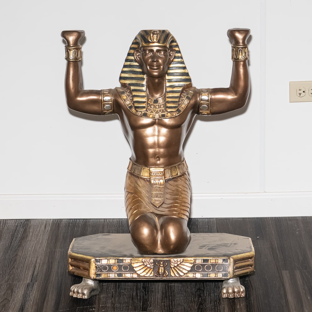 Kneeling Pharaoh: This striking composite resin statue captures a kneeling Egyptian pharaoh in a ceremonial pose, rendered with a faux-bronze finish and accented by traditional gold-tone "nemes" headcloth striping. The