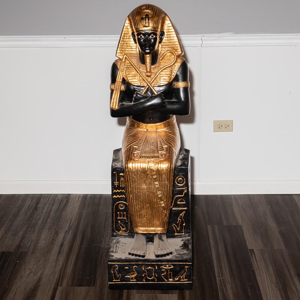 Egyptian Revival Resin King Tut Statue: This impressive large-scale figure captures the iconic image of King Tutankhamun in a classic seated pose, complete with the traditional Nemes headdress, crook, and flail. Crafted from hollow resin