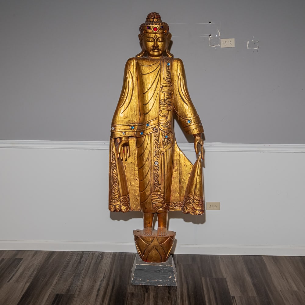 Large Gilded Thai Buddha Standing Statue: Standing as a striking example of Southeast Asian-inspired religious decor, this tall, slender Buddha figure is crafted in a traditional Thai "Abhaya Mudra" (dispelling fear) or "Varada Mudra" style,