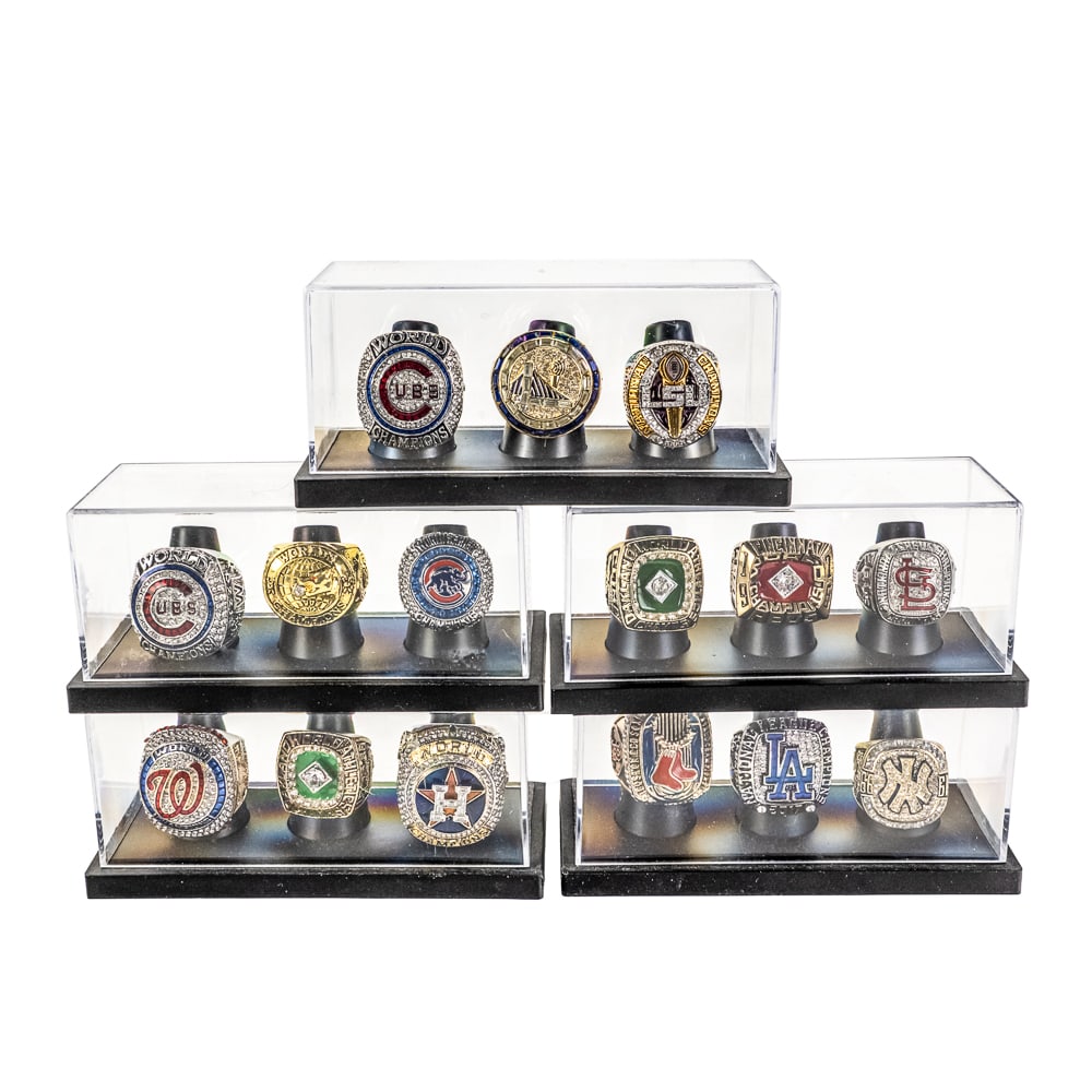 (15) Assorted Championship Rings MLB NBA +: Collection of (13) assorted MLB "World Series Championship Rings" including The Cub, Red Sox, Athletics, Reds and several others including a LSU (College) & Golden State (NBA) showcased inside display