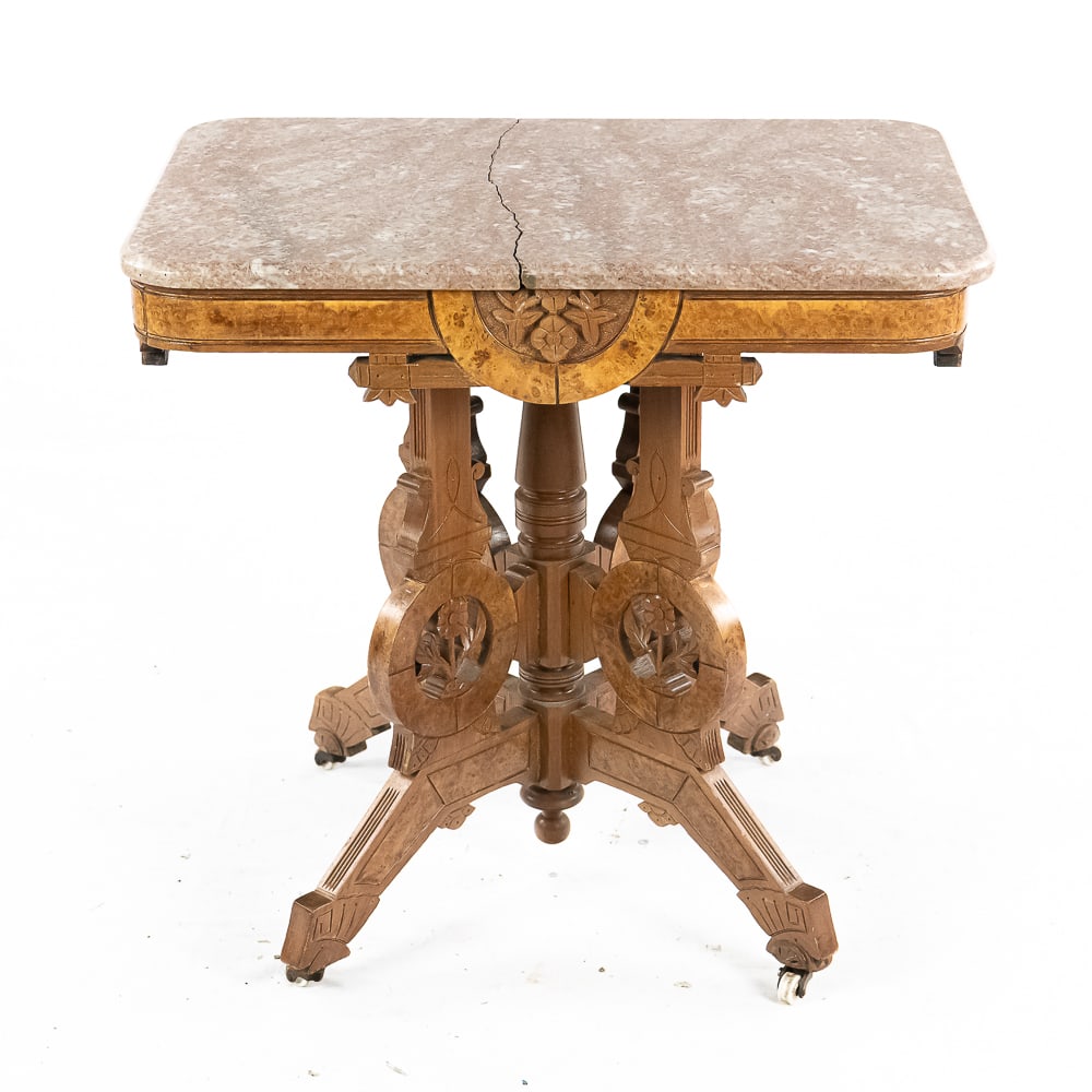 Victorian Marble Top Side Table: Classic walnut Victorian side table with burl veneer and 4 carved and saw cut legs on white porcelain casters. Pink marble top is cracked in two. Measures 30" wide, 29" tall, 20" deep. No shipping on