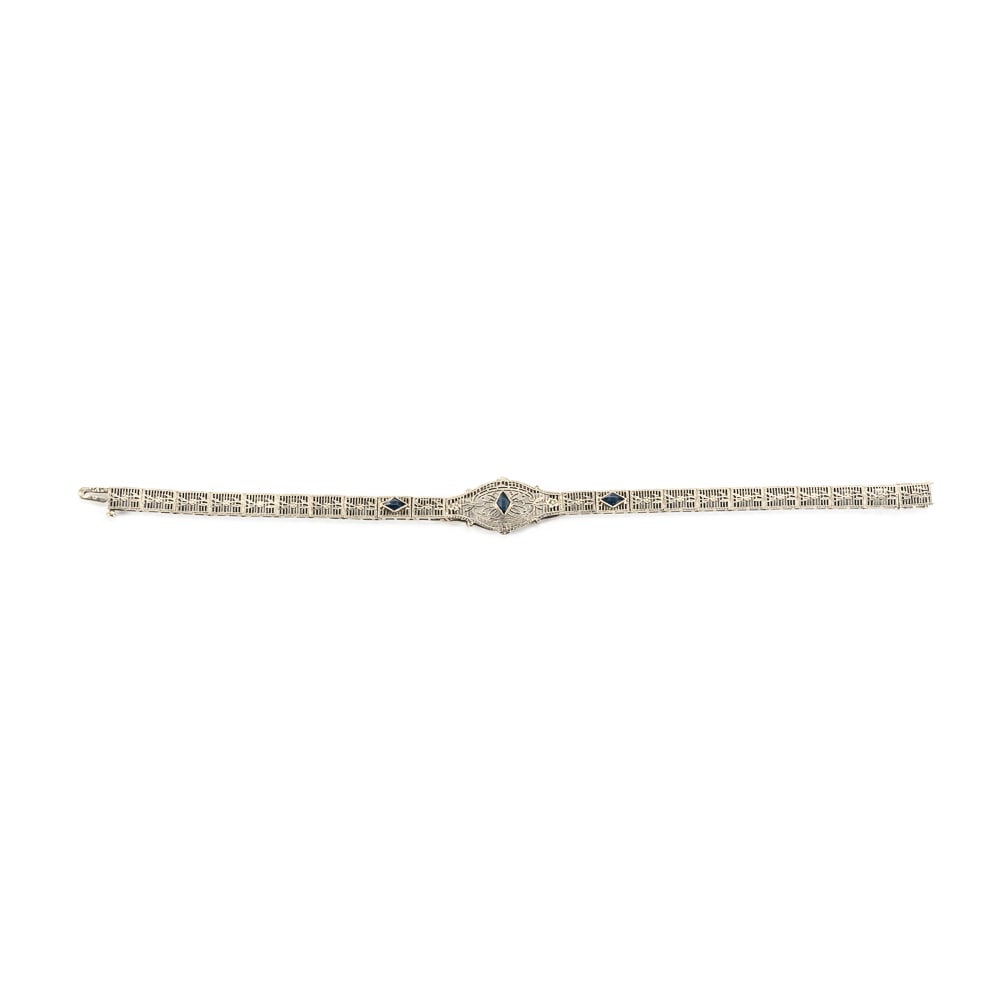 10k White Gold Sapphire Accented Filigree Bracelet: Attractive 10k white gold sapphire accented 7" filigree bracelet. Lovely 21 panel Art Deco white gold construction showcasing center marquee with diamond shaped sapphire accents exemplifying an elabor