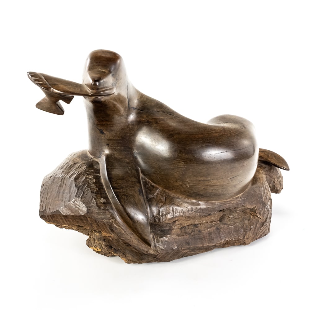 Hand-Carved Wood Seal W/Fish in Mouth: A mid-century modern style sculpture of a reclining seal or sea lion, hand-carved from a dense, dark hardwood—likely ironwood or walnut—with a minimalist, fluid aesthetic. The piece