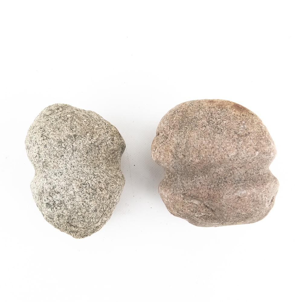 Pair of Native American Grooved Mauls (2): This pair of prehistoric-style stone mauls features the classic full-groove design, meticulously pecked and ground into dense, heavy cobbles—likely granite or greenstone. These utilitarian