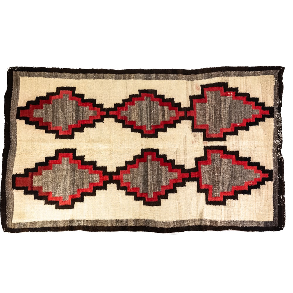 Navajo-Style Geometric Wool Rug: This hand-woven textile features a striking Native American Navajo-style design, showcasing a repeating pattern of serrated diamond and arrowhead motifs in a bold palette of grey, red, cream, and