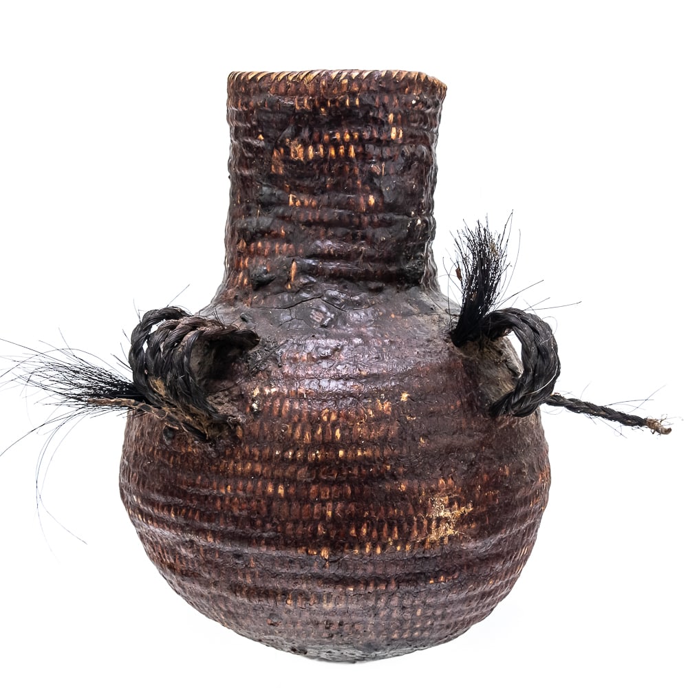 1920s Apache Water Vessel: This circa 1920s Apache Tus water vessel showcases the ingenuity and craftsmanship of the Apache people. Featuring a bulbous base and narrow neck it is constructed using a coiled basketry technique