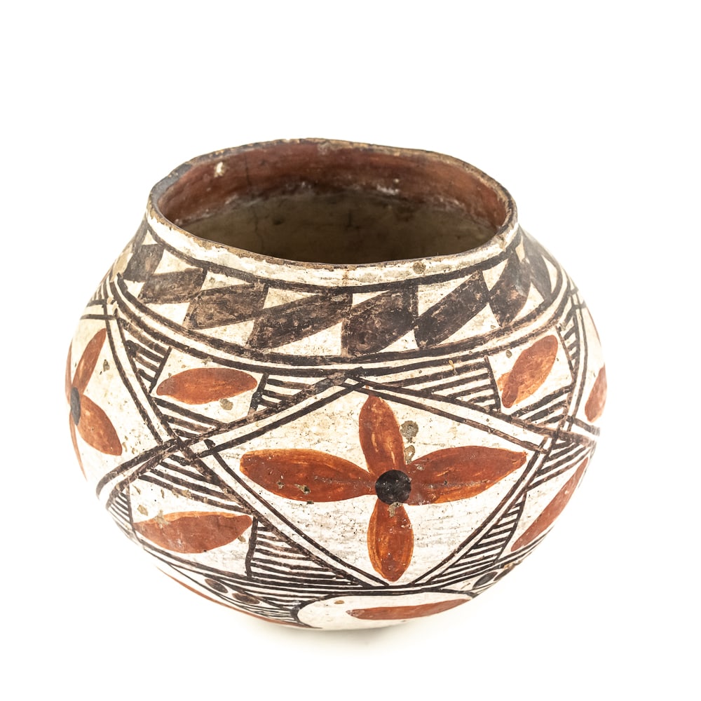 1920s Laguna Pueblo Polychrome Pot: This black and red on white polychrome pot was made at Laguna Pueblo New Mexico and attributed to the 1920s. It features a mix of geometric lines as well as floral designs incorporated within. The sur