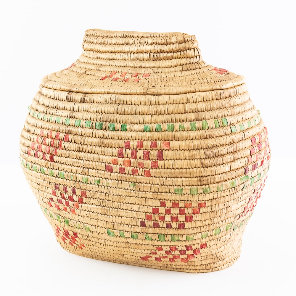 1960s Yupik Eskimo Basket: This oval coiled grass basket dates from the mid-20th century. It is constructed upwards from a central knot at the base. The coils are sewn together with grass thread and the exterior is decorated