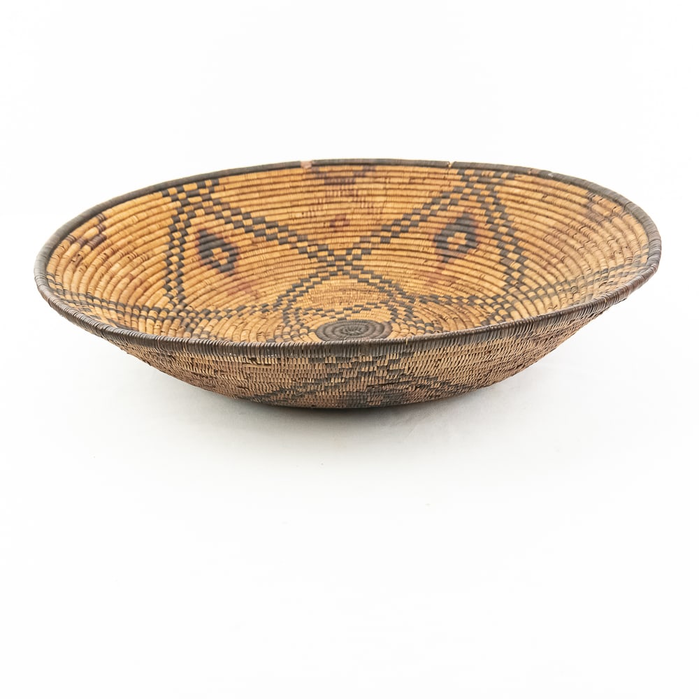 1910 Western Apache Bowl: A finely woven coiled basket tray or shallow bowl, circa 1910. While its characteristic strongly aligns with Western Apache coiled basketry, there's a possibility that it could be Jicarilla Apache, as