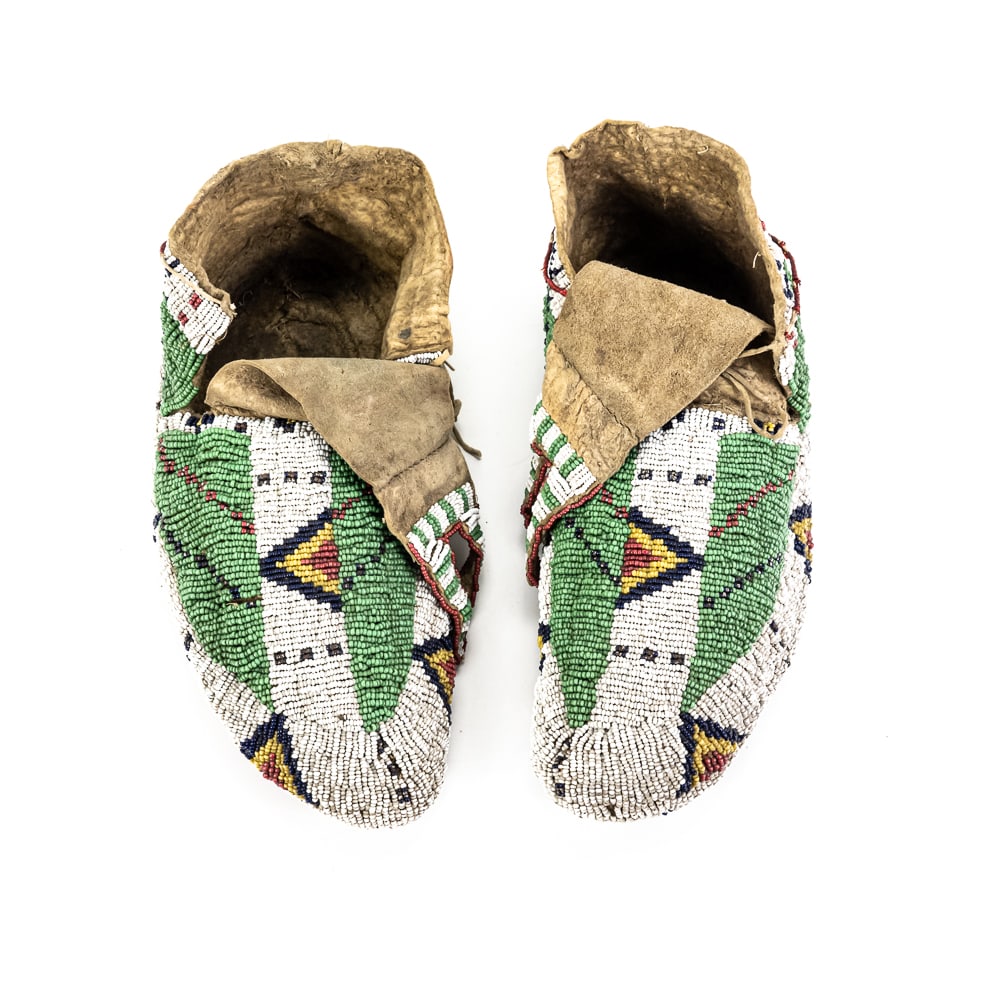 Native American Fully Beaded Moccasins Pair: These striking Native American moccasins are a masterclass in Plains-style artistry, likely dating from the late 19th to early 20th century. According to the accompanying provenance note, these