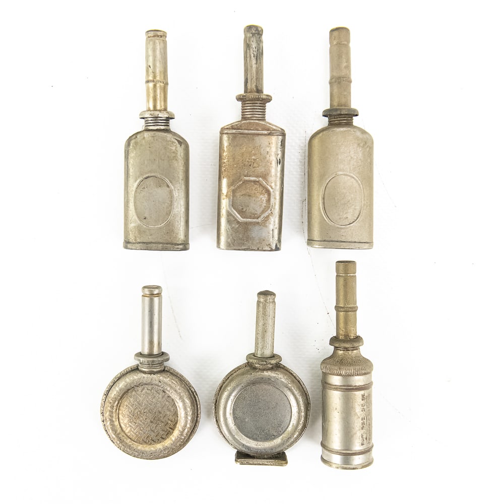 Six-Piece Lot of Various Oil Cans: Includes three rectangular oil cans with caps, two round oil cans with caps, and one cylindrical shaped round oil can with caps. All in as-found condition. Can use a good cleaning. See photos for