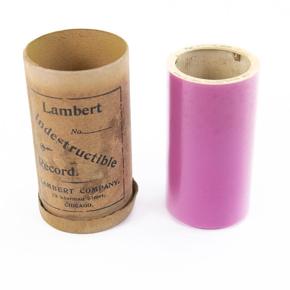 Pink Lambert Cylinder Record # 275: #275 singing Girl, March - Orchestra. Nice even pink color. Old crack on title edge with old glue repair might slightly affect last 1/5 of audio track. Barely fits all the way on the end of the mandre