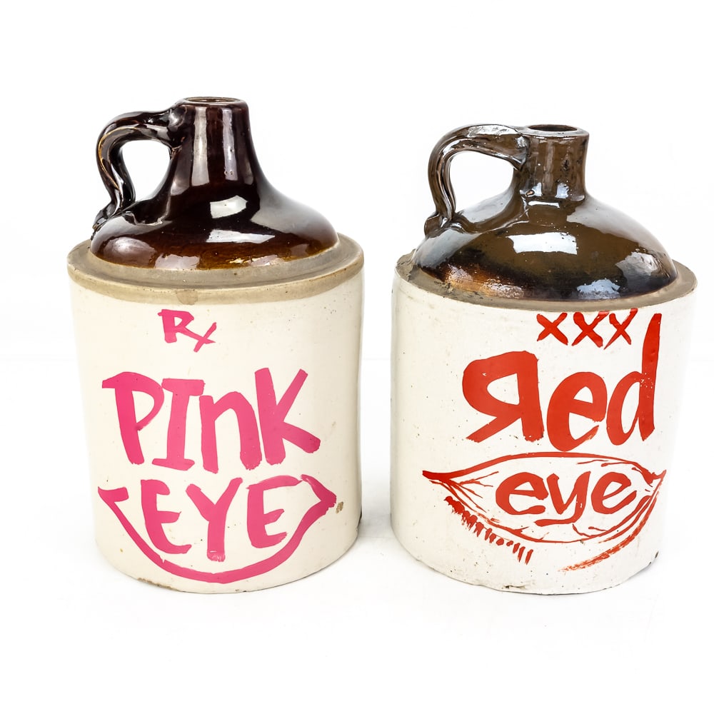 (2) Vintage Monmouth Pottery Stoneware Jugs: (2) Vintage Monmouth Pottery Stoneware Jugs, decorated with custom paint "Pink Eye" and "Red Eye", moonshine whiskey jug, two-tone brown top and tan base, age-related wear, some chips, no cracks,