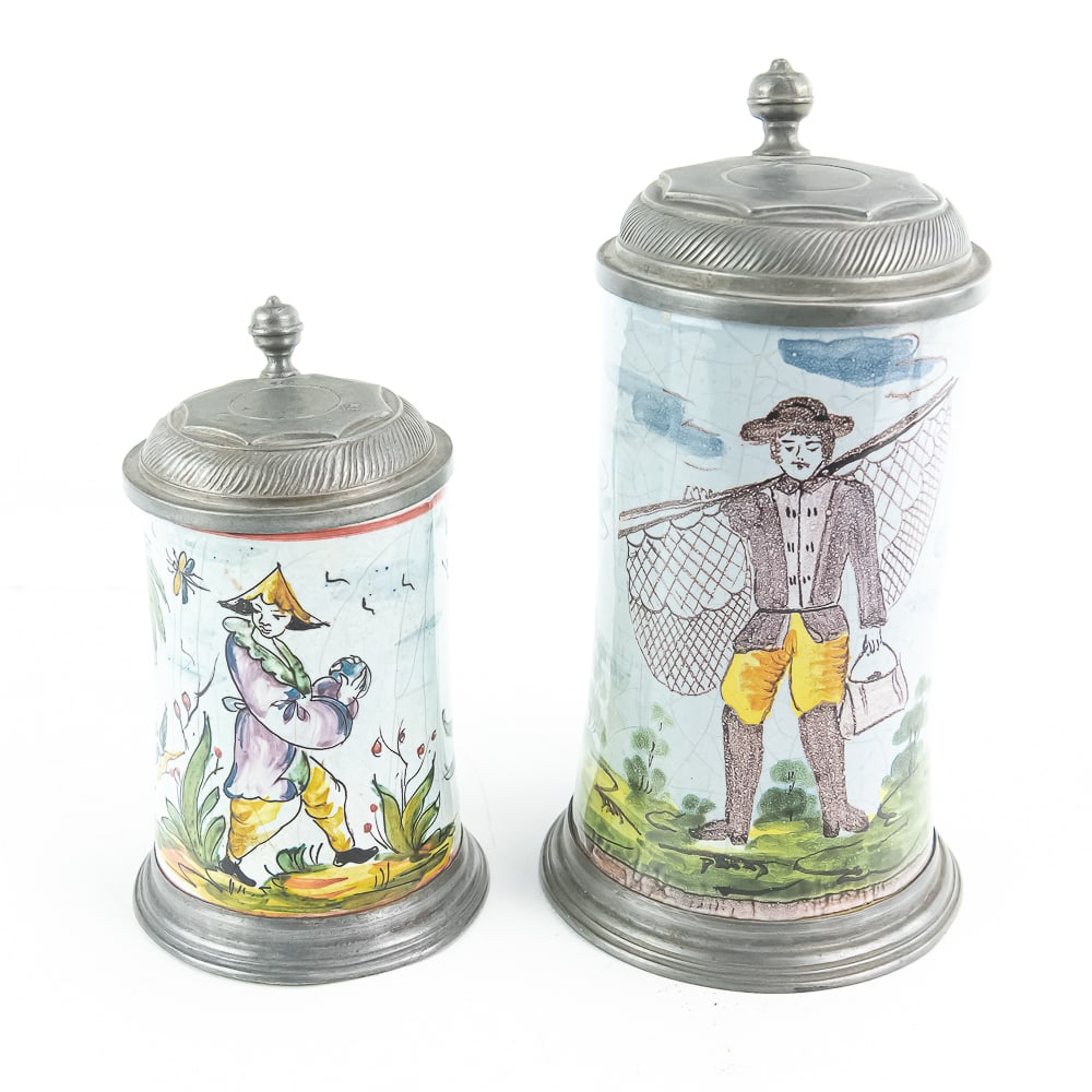 2 Rare German Faience Beer Steins: With pewter hinged lids. Both have heavy crazing yet quite unique and beautiful. The larger stein depicts a fisherman with bag and net and measures approximately 10"T to top of Finial - it appears to