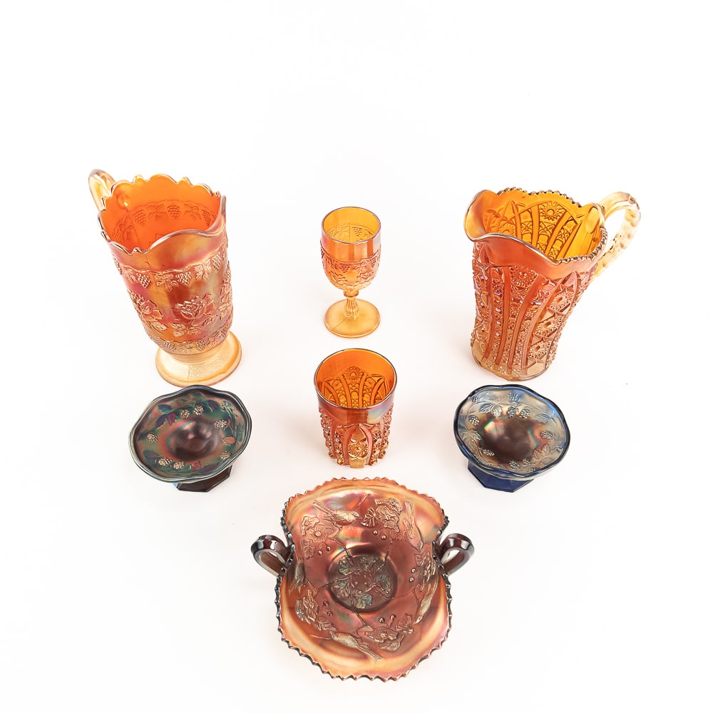 Carnival Glass Mixed Assortment: 7-Pc Lot: Includes two blue miniature Blackberry compotes (base chips), an Imperial Octagon small milk pitcher in marigold (large collar base chip), a Fenton Wine and Roses cider pitcher in marigold (large inte