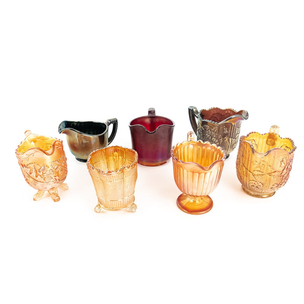 Carnival Glass Creamers: 7-Pc Lot: Includes an Imperial Chesterfield in red (large base chip), Imperial Pansy in marigold (good condition), Imperial Pansy in amethyst, Imperial Smooth Rays in black amethyst, Fenton Stippled Rays in mar
