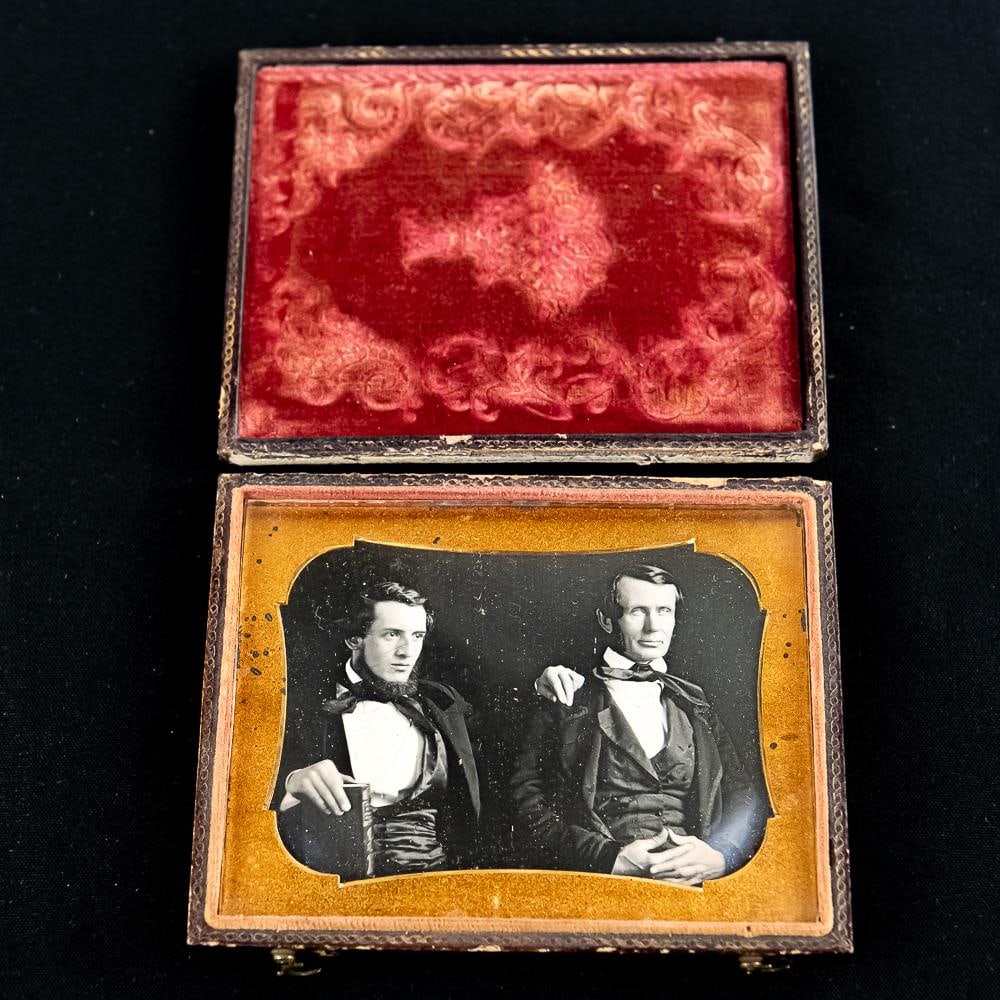 1/4 Plate Daguerreotype of 2 Men: 1/4 plate horizontal Dag of 2 well dressed seated men. The younger man on the left is holding a book in his right hand and has his left hand on the shoulder of the older man. They might possibly be