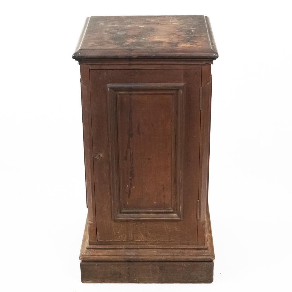 Victorian Wooden Document Pedestal Cabinet: This late 19th-century Victorian-era wooden document cabinet is constructed with a single hinged paneled door, a stepped pedestal-style molding base, and heavy top molding. The interior is fitted