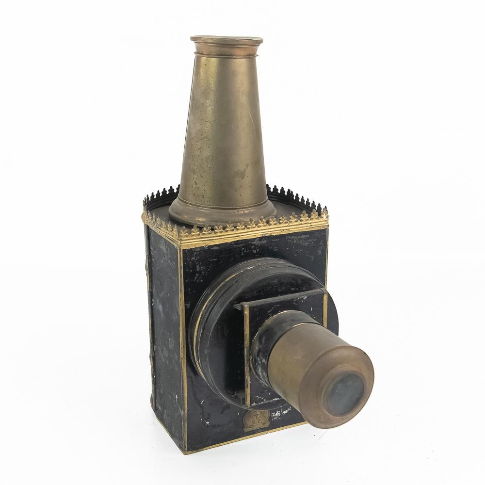 Vintage Magic Lantern Projector: This fascinating 19th-to-early-20th-century magic lantern optical projector features a classic tinplate and brass construction, complete with a prominent top chimney and a front projection lens