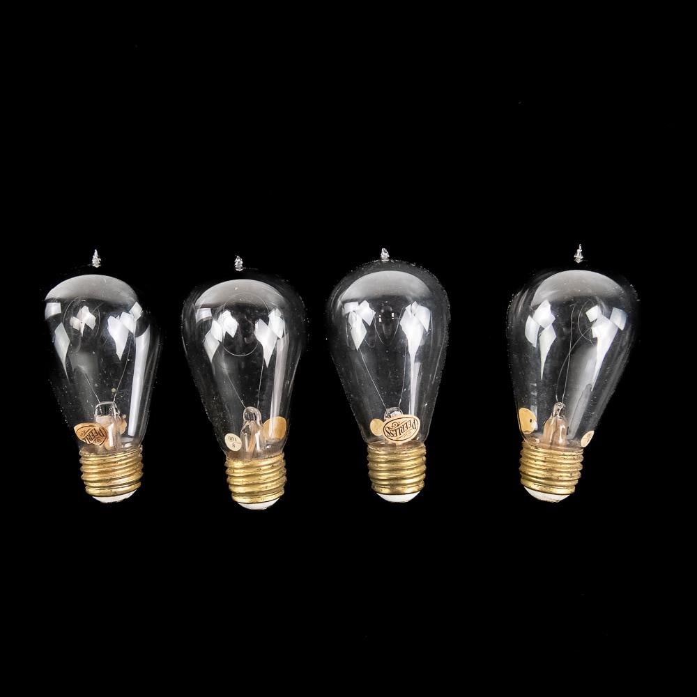 4 Antique Peerless Tipped Light Bulbs: An exceptional set of four early 20th-century antique clear glass tipped incandescent light bulbs featuring brass screw bases and prominent internal loop filaments. Each bulb retains its original