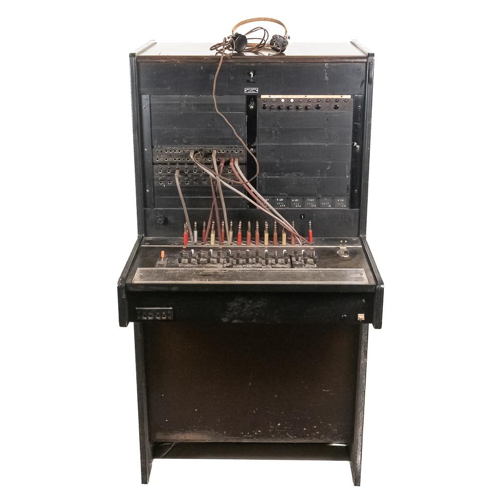 Vintage Western Electric Switchboard: This vintage Bell System telephone switchboard console, manufactured by Western Electric, represents early-to-mid 20th-century telecommunications history with its dark cabinet, intricate array of patc