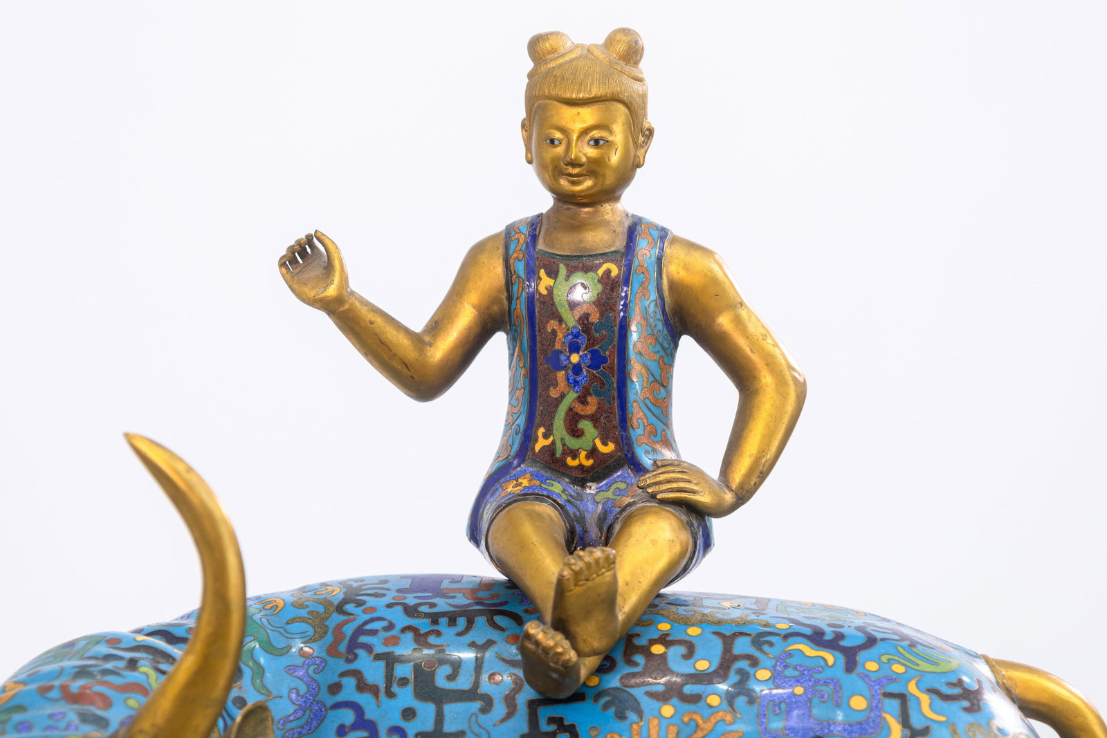 Vintage Chinese Cloisonne Bull Sculpture with Sitting Figure Asian Collectables: A vintage Chinese cloisonne sculpture depicts a golden-horned bull adorned in rich blue enamel decorated with intricate multicolored patterns. A seated figure with gilt accents rests gracefully on the