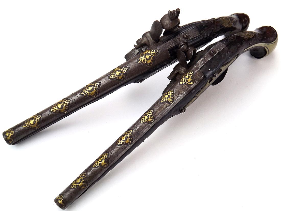 Pair of 18th C. Islamic Ottoman Turkish Battle: An attractive pair of large Ottoman flintlock holster pistols. Having an unusual and seldom encountered chiseled and heavily gold inlaid barrel decorations. Carved wooden stocks with brass mounts. Bot