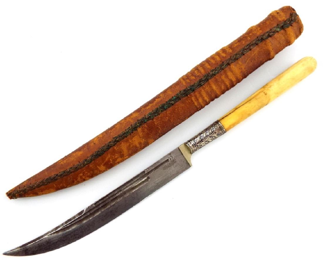 19th C. Islamic Turkish or Russian Caucasian "Kard": A lovely dagger of an elegant form with a multi-fullered lightly curved blade and bone grip, having a large Niello silver bolster. In its original leather scabbard. Total Length - 9 7/8" Blade length: