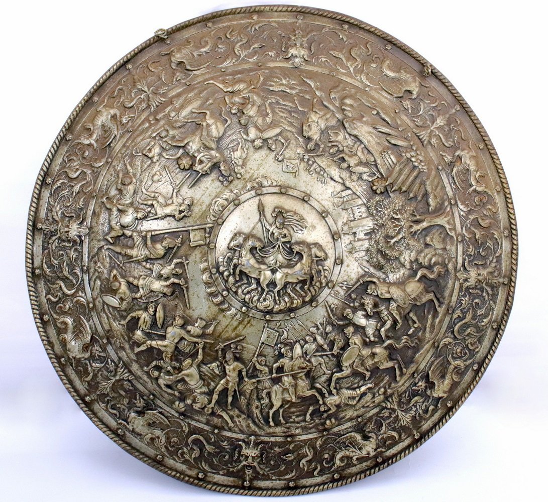 Impressive Large Iron Shield in Italian or Spanish 16th: Impressive Large Iron Shield in Italian or Spanish 16th Century Parade Armor Style. Large and heavy piece, extremely ornate having high relief Medieval Battle-scenes all around with carved castle on f