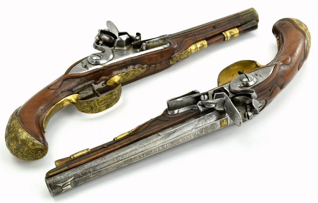 A wonderful pair of engraved and gilded 1770s Bavarian: A wonderful pair of engraved and gilded 1770s Bavarian flintlock pistols by Kuchenreuter. Featuring silver encrusted barrels flared at the muzzle, lock safety, relief carving on the walnut stocks and 