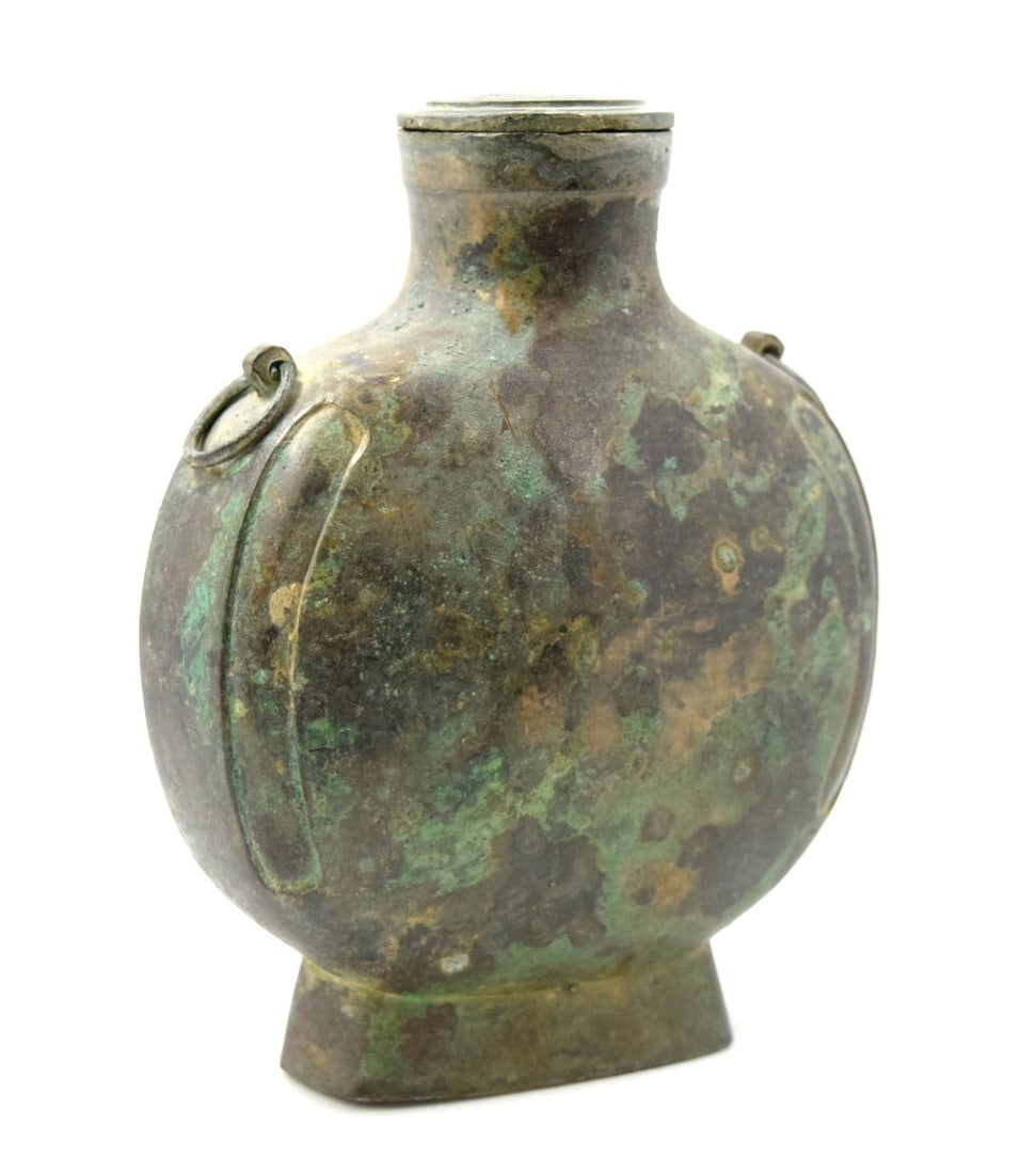 Chinese Archaic Bronze Wine Vessel Bian hu Han Dynasty: A bronze container for wine, bian hu, the flattened, oval-shaped body supported on a stepped foot of square section and surmounted by a round neck which terminates in a lipped mouth. Size: 6 3/4" x 5 