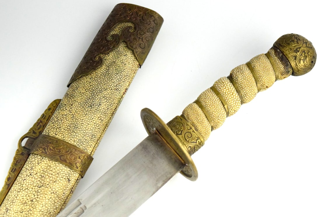 Antique Chinese Saber (Dao) with Shagreen-Style Grip & Scabbard, Engraved Brass Mounts: Chinese single-edged saber (dao), featuring a gently curved blade with a long narrow fuller running along the upper portion of the blade. The hilt is fitted with a circular brass guard (disc form) wit