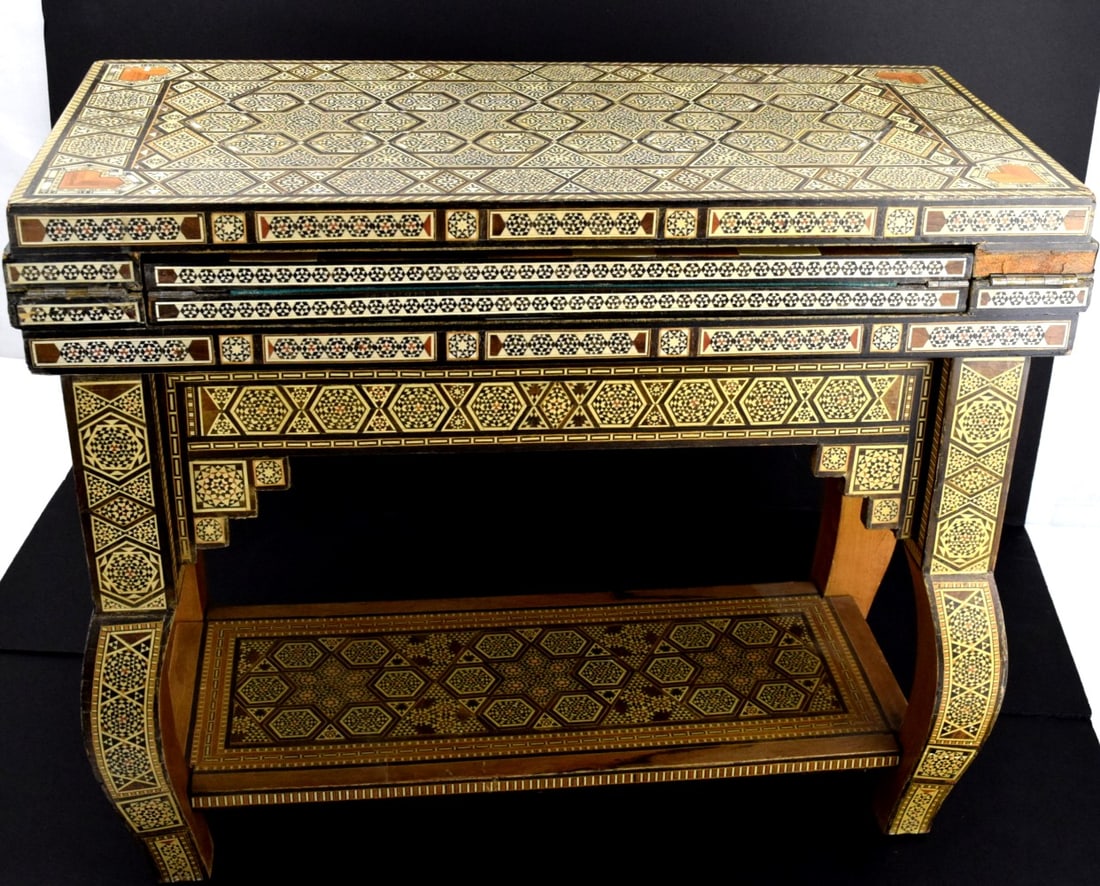 PROFUSELY INLAID SYRIAN MIDDLE EASTERN GAME TABLE: Here is a very fine Syrian folding games table. The piece is completely hand-crafted and inlaid with quality wood in a mosaic pattern, with cabriolet legs and a bottom shelf. This is the famous "Orien