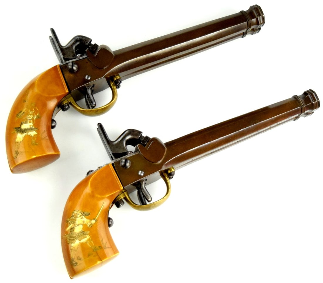 AN EXTREMELY RARE 1860 AND UNIQUE MATCHED PAIR OF DOUBLE BARREL JAPANESE PERCISSION CARRIAGE PISTOLS: The pistols with cannon muzzles and frames of sentoku (brass of bronze) both well stamped with Meiji registration numbers. Steel hammers and triggers. The butts of stained noble material and inlaid wi