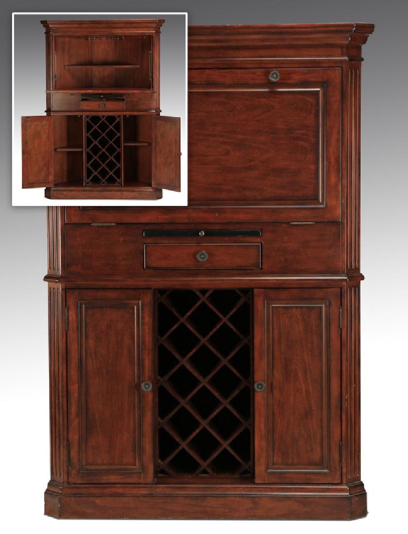 Carved corner cabinet with wine storage, 66"h: Contemporary carved corner cabinet with dropleaf front, the stepped pediment surmounting the dropleaf door opening to reveal two fitted shelves above one drawer with pull-out granite top, surmounting 