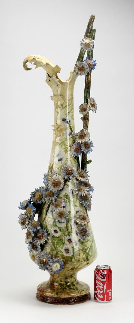 Monumental majolica floral ewer, ca 1900, 40"h: Monumental Continental majolica flower encrusted ewer, circa 1900, having high relief blue corn flowers spilling down the side on a mottled grey ground, with a twig form handle and a figural leaf form