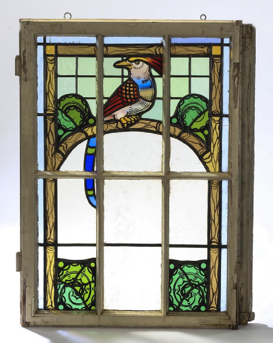 Early 20th c. English stained glass window w/ bird: Early 20th century English stained glass window, depicting a red and yellow Ho Ho bird seated in profile within an arched architectonic frame resembling tree branches, flanked by stylized greenery, th